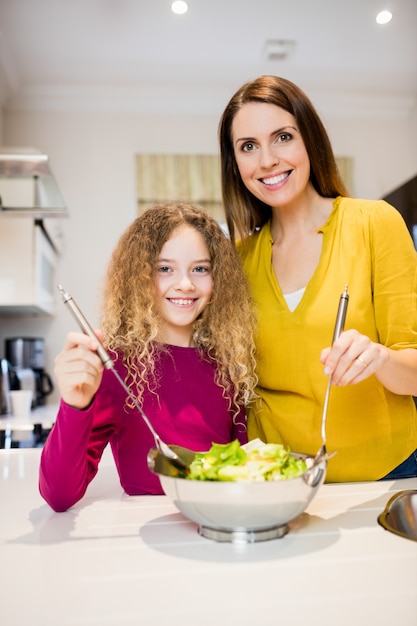 Foto gratuita madre aiutare la figlia a fare insalata