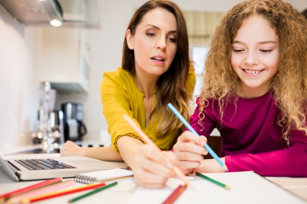 Mother assisting her daughter in drawing