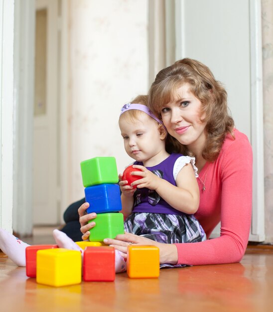 mother and baby girl plays with blocks in home