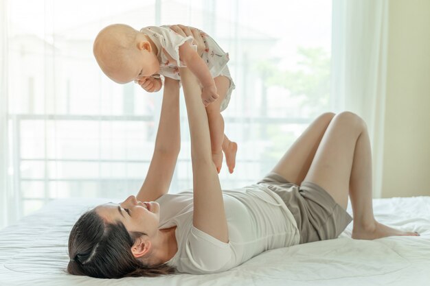 Mother and baby playing in the bed 