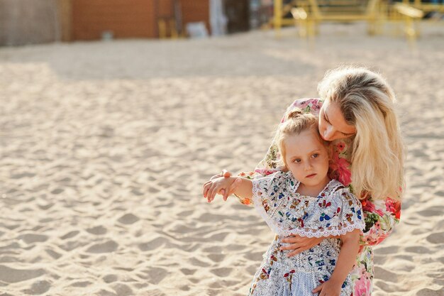 Mother and beautiful daughter having fun on the beach Portrait of happy woman with cute little girl on vacation