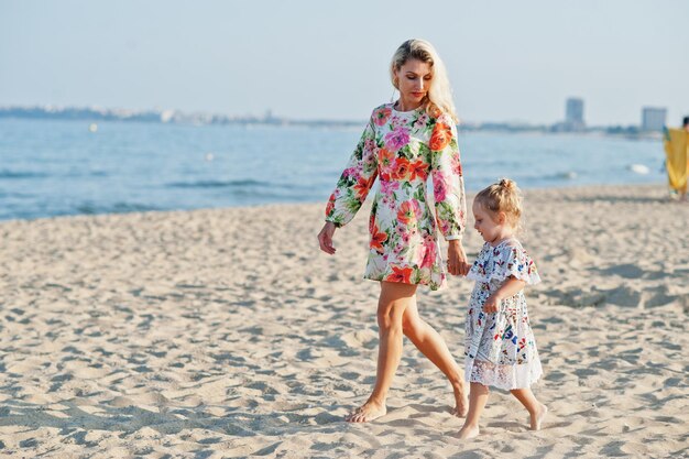 Mother and beautiful daughter having fun on the beach Portrait of happy woman with cute little girl on vacation