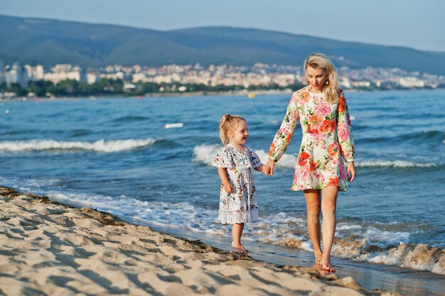 ビーチで楽しんでいる母と美しい娘休暇中のかわいい女の子と幸せな女性の肖像画