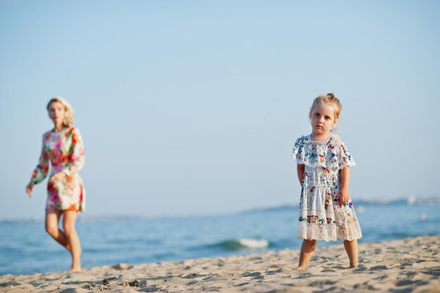 Mother and beautiful daughter having fun on the beach Portrait of happy woman with cute little girl on vacation