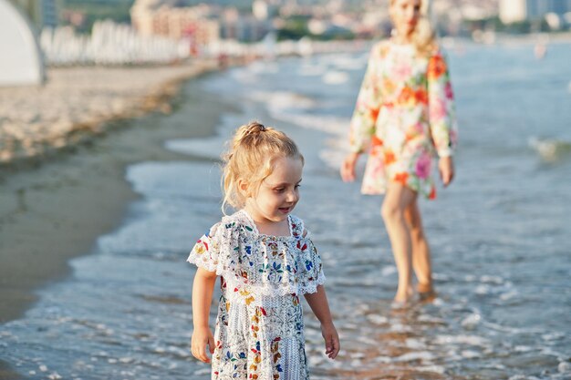 Mother and beautiful daughter having fun on the beach Portrait of happy woman with cute little girl on vacation