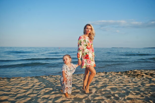 어머니와 해변에서 즐거운 시간을 보내는 아름다운 딸 휴가에 귀여운 소녀와 함께 행복 한 여자의 초상화