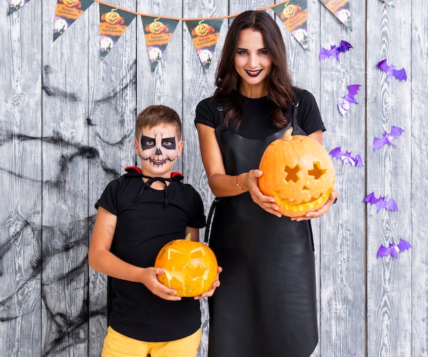 Free photo mother and boy holding carved pumpkins