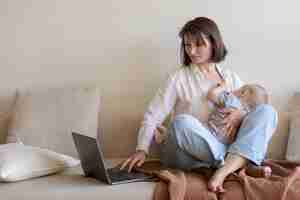 Free photo mother breast feeding her child while working