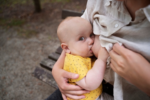 Vista laterale del bambino che allatta al seno della madre