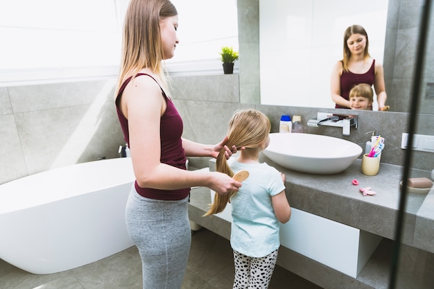 Free photo mother brushing hair of daughter