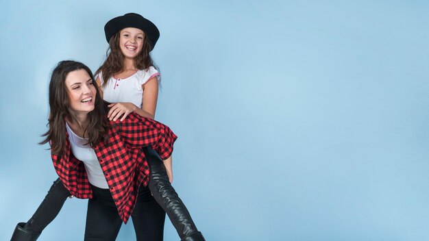 Mother carrying daughter in hat on back