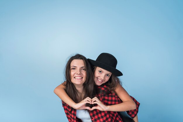 Mother carrying daughter showing heart from hands on back