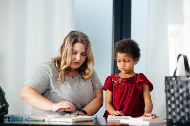 Mother and child daughter draws creatively at home at the table