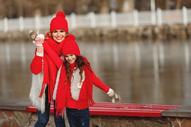 Mother and child in knitted winter hats on family Christmas vacation. Handmade wool hat and scarf for mom and kid. Knitting for kids. Knit outerwear. Woman and little girl in a park.