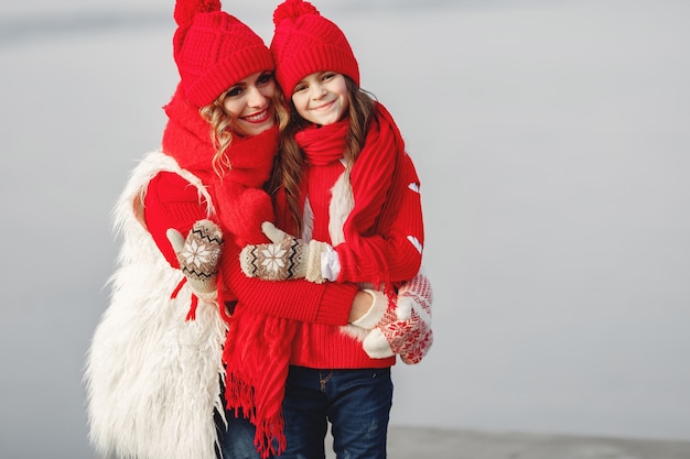 Mother and child in knitted winter hats on family Christmas vacation. Handmade wool hat and scarf for mom and kid. Knitting for kids. Knit outerwear. Woman and little girl in a park.