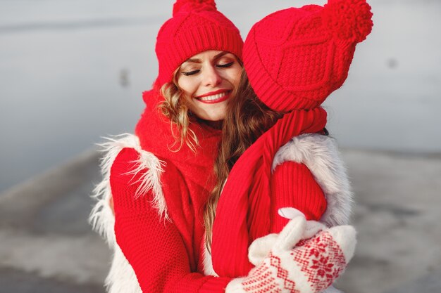 Mother and child in knitted winter hats on family Christmas vacation. Handmade wool hat and scarf for mom and kid. Knitting for kids. Knit outerwear. Woman and little girl in a park.