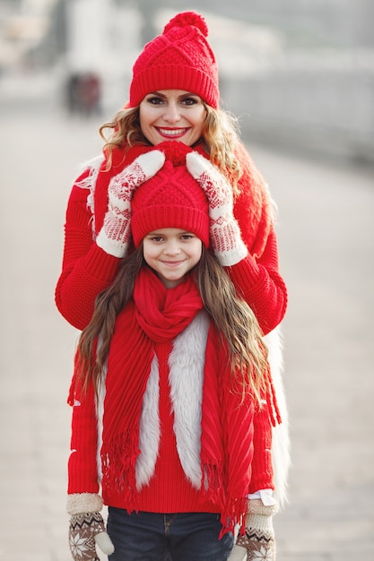엄마와 가족 크리스마스 휴가에 니트 겨울 모자에 아이. 엄마와 아이를위한 수제 양모 모자와 스카프. 아이들을위한 뜨개질. 니트 겉옷. 여자와 공원에서 어린 소녀입니다.