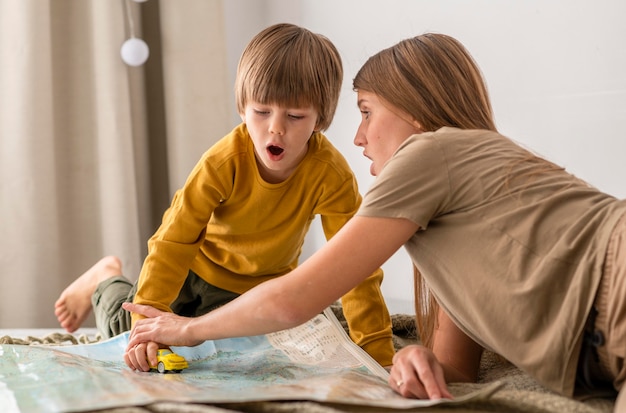 Madre e bambino che giocano insieme con la figurina dell'auto e la mappa