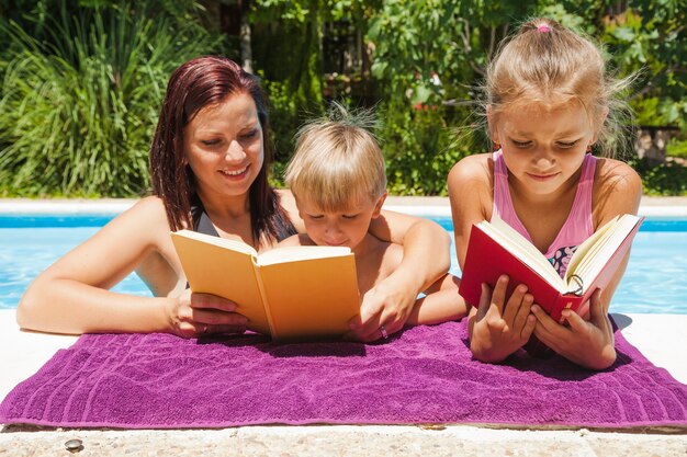 母親と子供たちがプールの読書に立っている