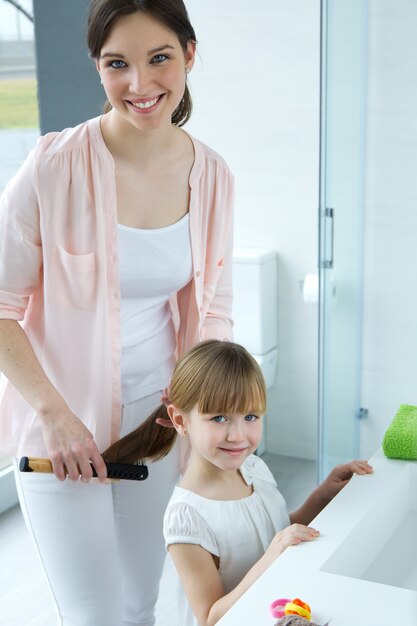 mother combing her daughter in the bathroom