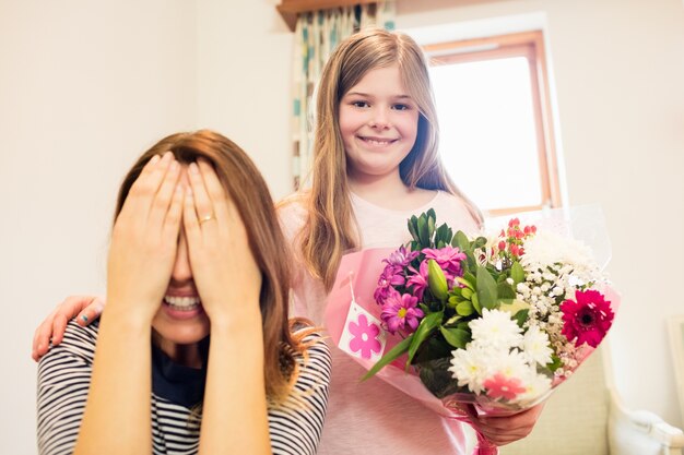 Free photo mother covering her eyes while receiving gift from daughter