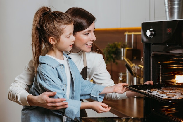 Mother and daughter baking cookies at home together