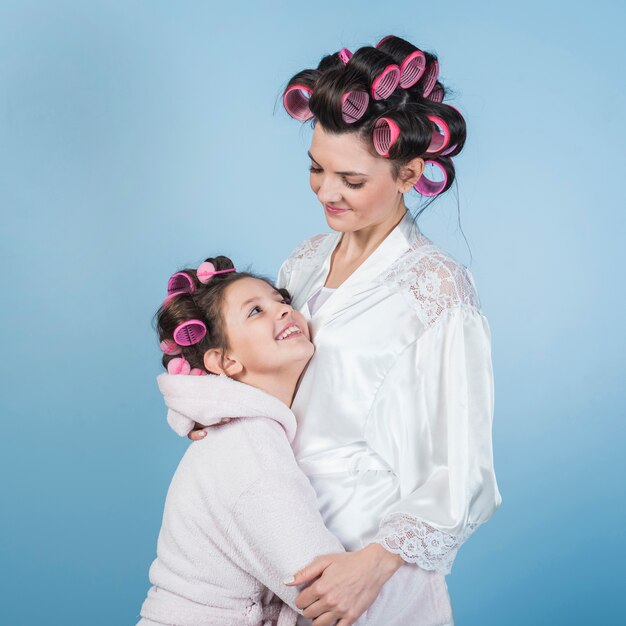Mother and daughter in bathrobes and curlers hugging
