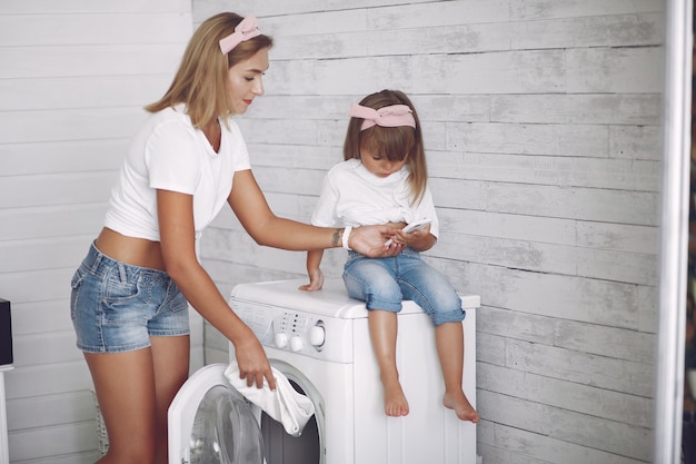 Mother and daughter in a bathroom near wash mashine