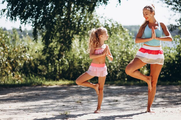 Mother and daughter at the beach practicing yoga