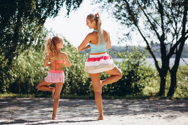 Mother and daughter at the beach practicing yoga