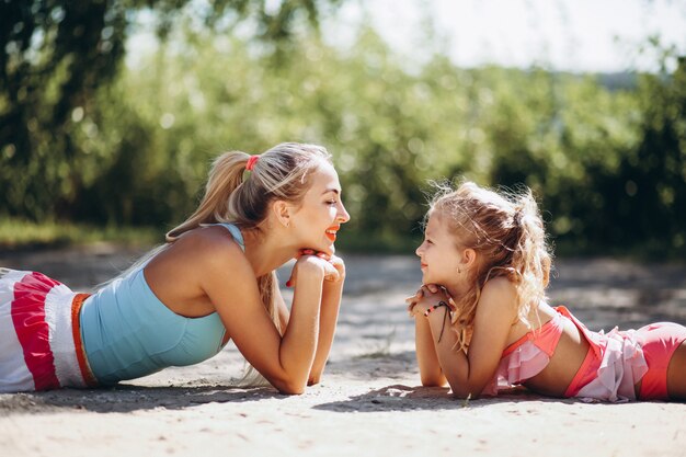 Mother and daughter at the beach practicing yoga