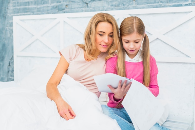 Mother and daughter in bed looking at papers 