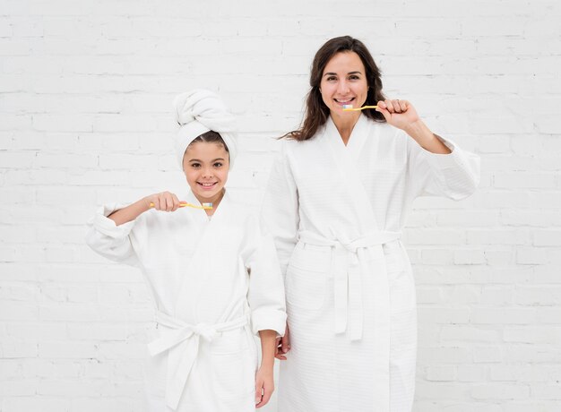 Mother and daughter brushing their teeth