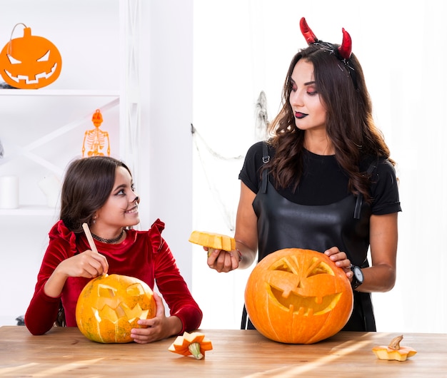 Mother and daughter carving pumpkins for halloween