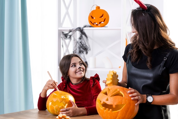 Mother and daughter carving pumpkins together