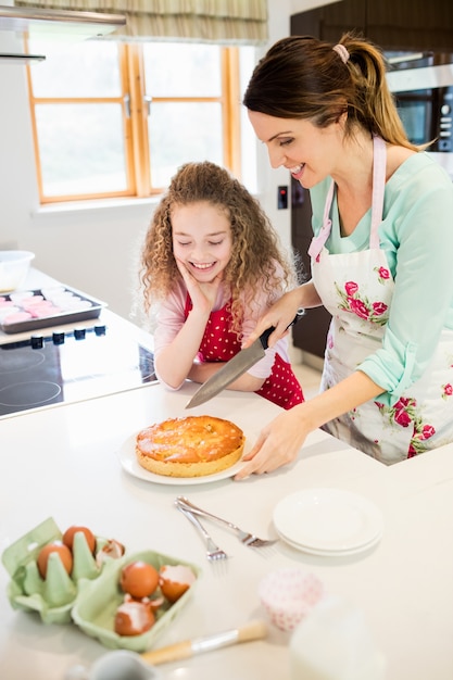 Mother and daughter cutting pancake in kitchen