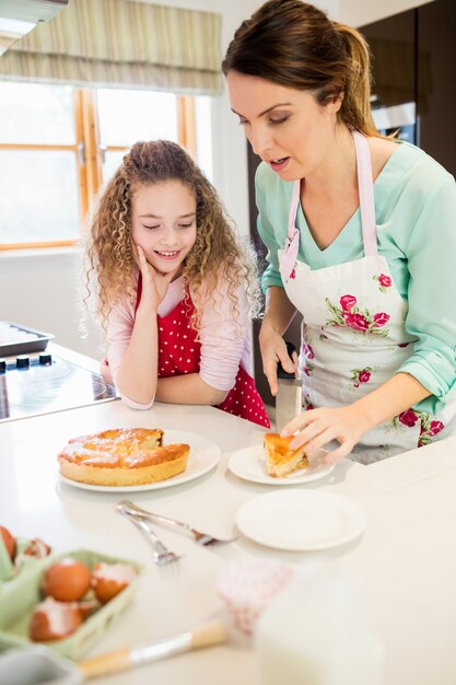 Mother and daughter cutting pancake in kitchen