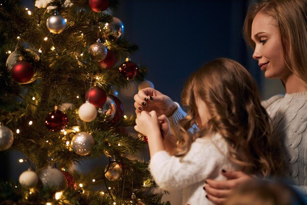 一緒にクリスマスツリーを飾る母と娘