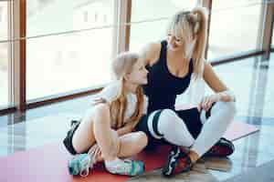 Free photo mother and daughter doing yoga in a yoga studio