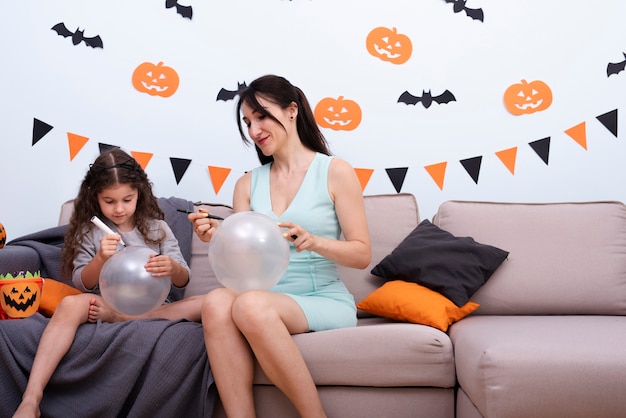 Mother and daughter drawing on balloons