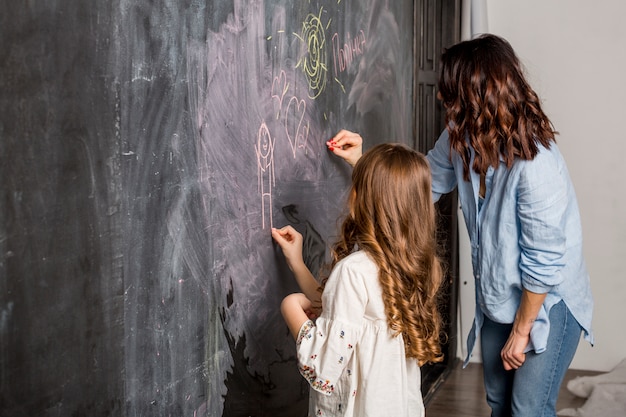 Mother and daughter drawing on blackboard 