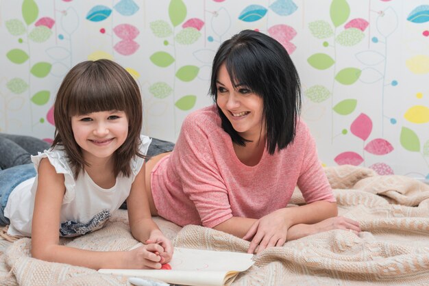 Mother and daughter drawing lying on bed