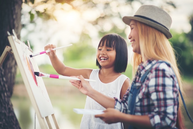 Free photo mother and daughter drawing picture together in the park