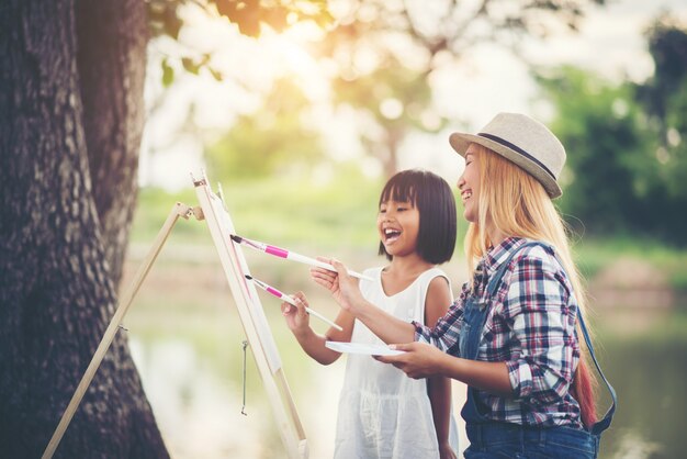 Мать и дочь рисуют картину вместе в парке