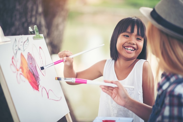 Free photo mother and daughter drawing picture together in the park