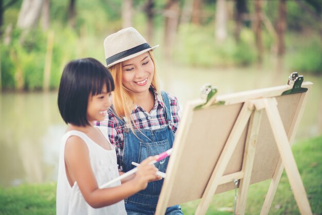 母と娘が一緒に公園に絵を描く