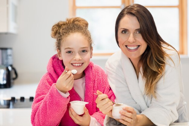 Mother and daughter eating ice cream in kitchen