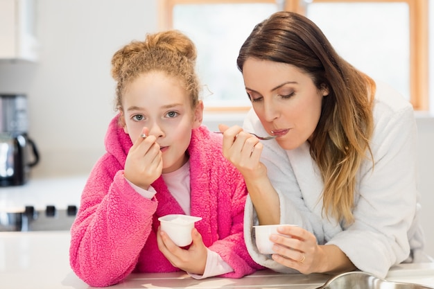 Mother and daughter eating ice cream in kitchen