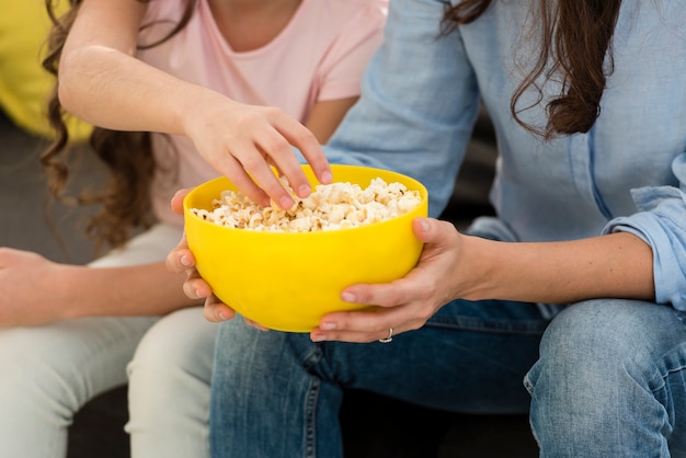 Mother and daughter eating popcorn close-up