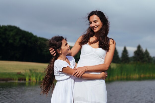 Mother and daughter embracing by the lake